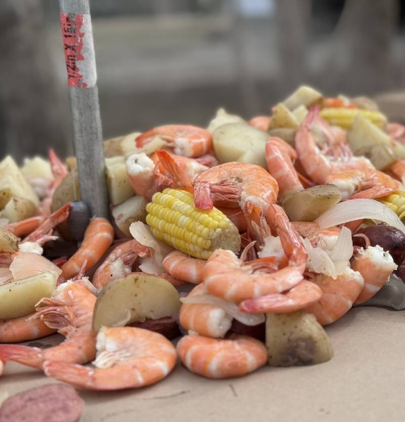 a table filled with a variety of seafood, including shrimp, potatoes, and corn