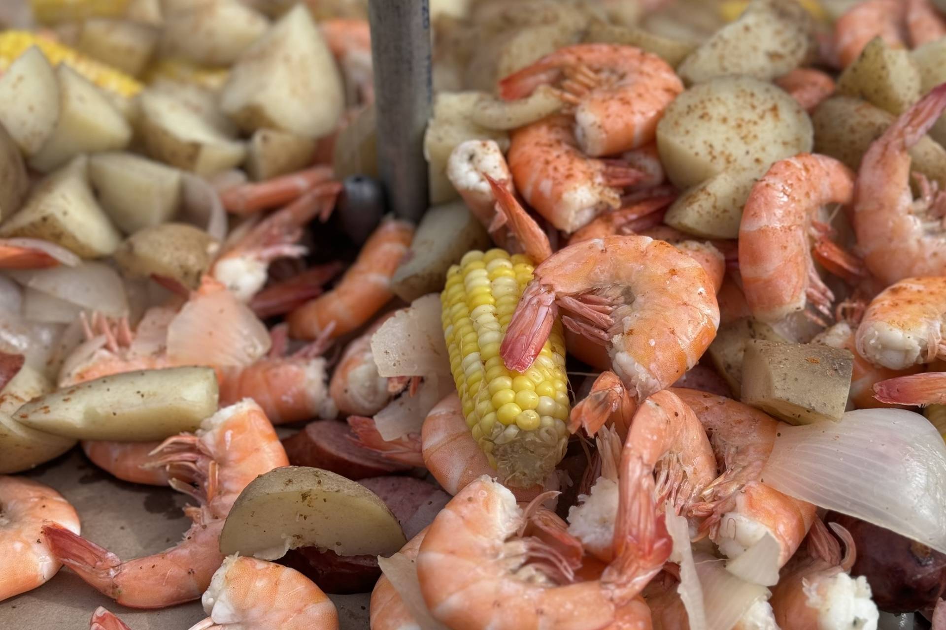 large pile of shrimp and potatoes, with the shrimp being the main focus